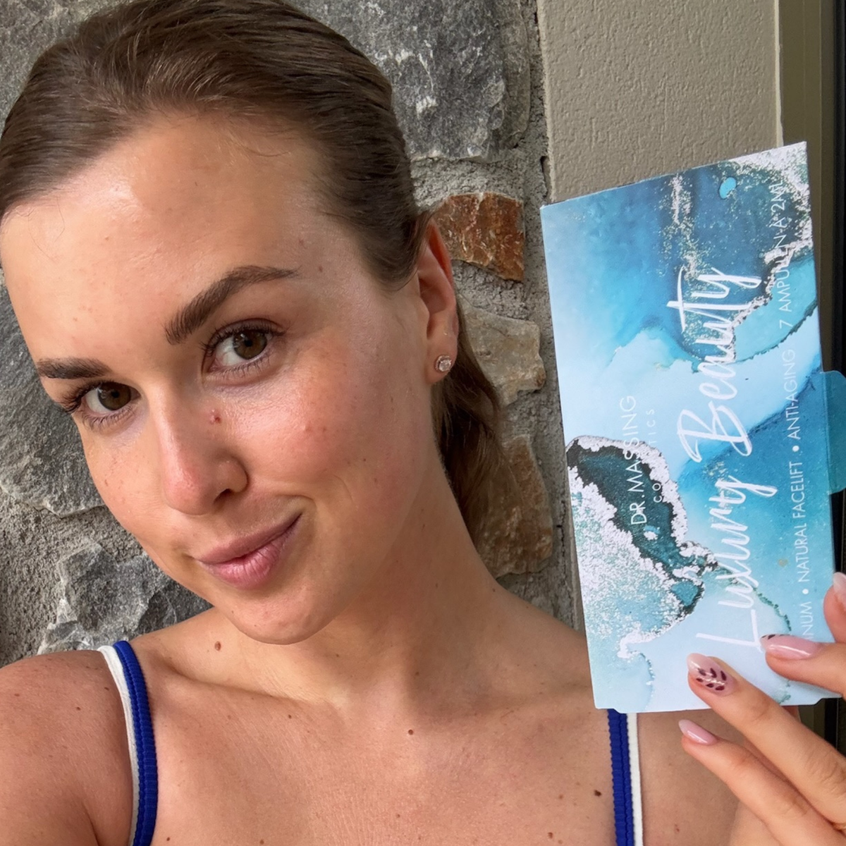 Frau hält Luxury Beauty Ampullen Box in der Hand neben ihr Gesicht und schaut in die Kamera