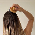 Eine Frau massiert ihre Kopfhaut mit dem Kopfmassager