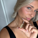 Frau hält Skin Repair Ampulle in der Hand neben ihr Gesicht und schaut in die Kamera