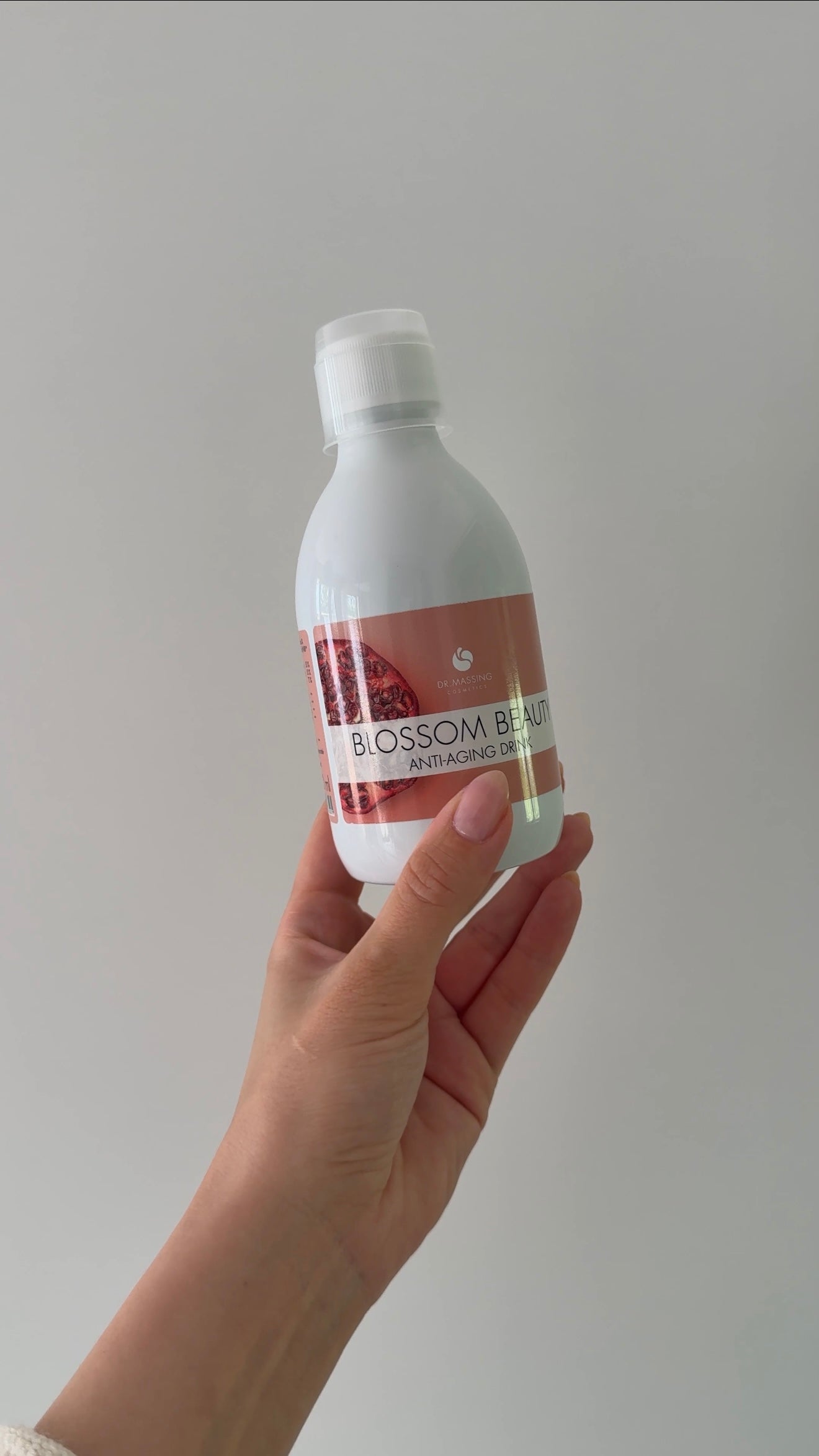 Eine Hand die den Blossom Beauty Anti-Aging Drink in die Kamera hält