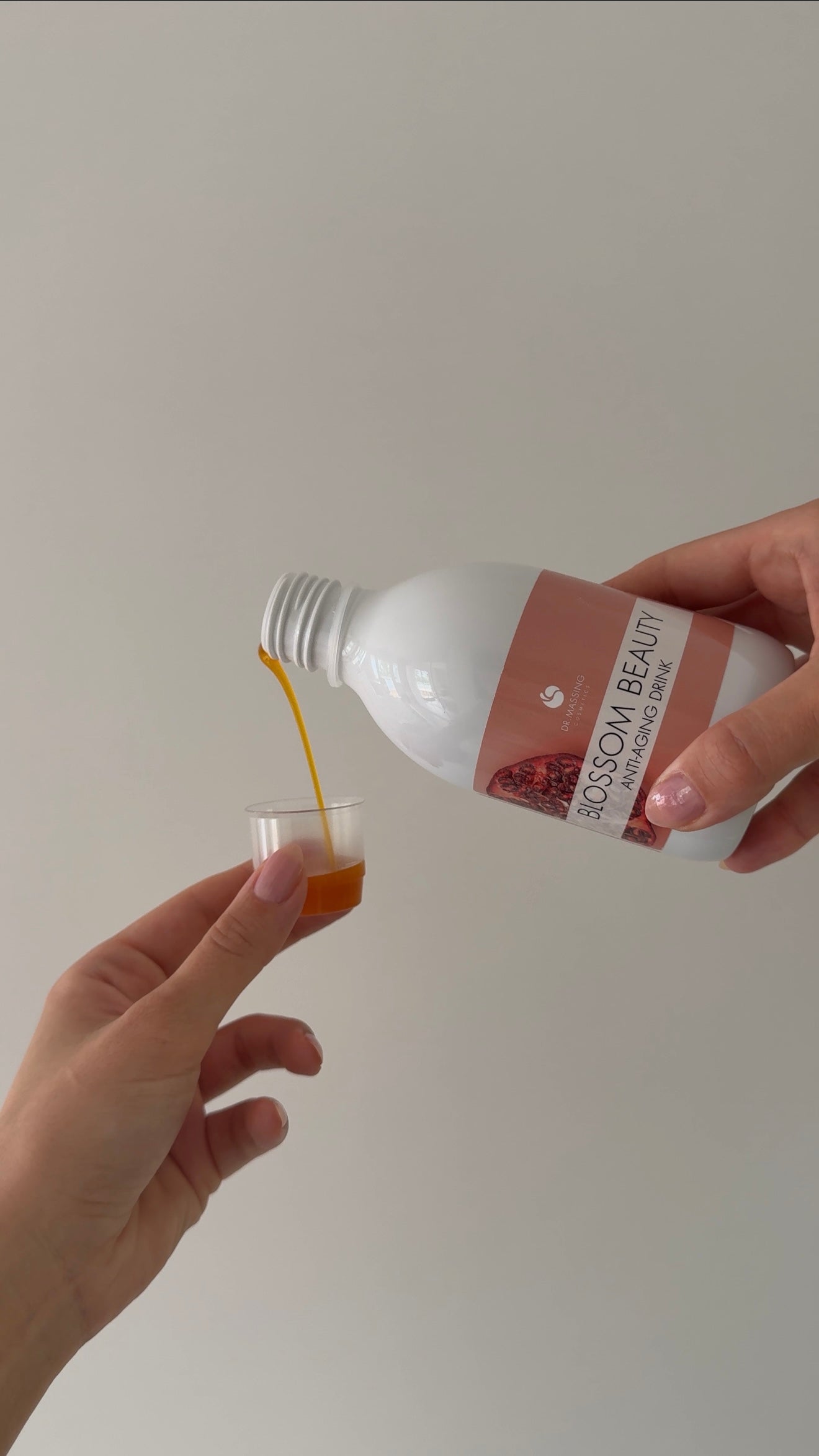 Eine Hand die den Blossom Beauty Anti-Aging Drink mit dem Messbecher dosiert