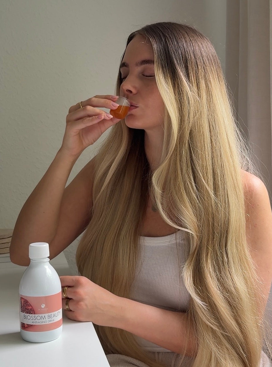 Eine junge Frau trinkt den Blossom Beauty Anti-Aging Drink mit geschlossenen Augen