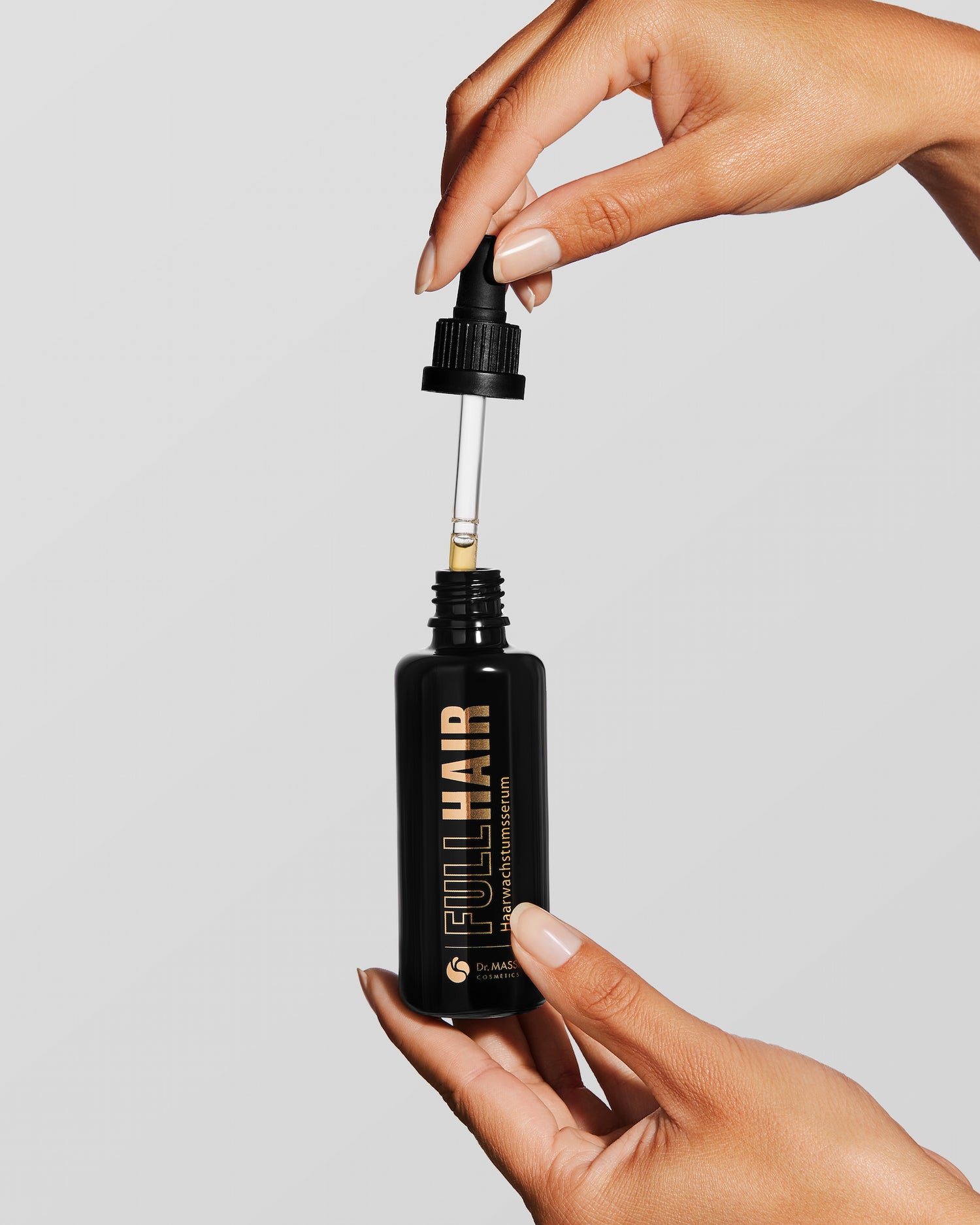 Frau hält Full Hair Serum in der Hand und hat die Pipette in der oberen Hand