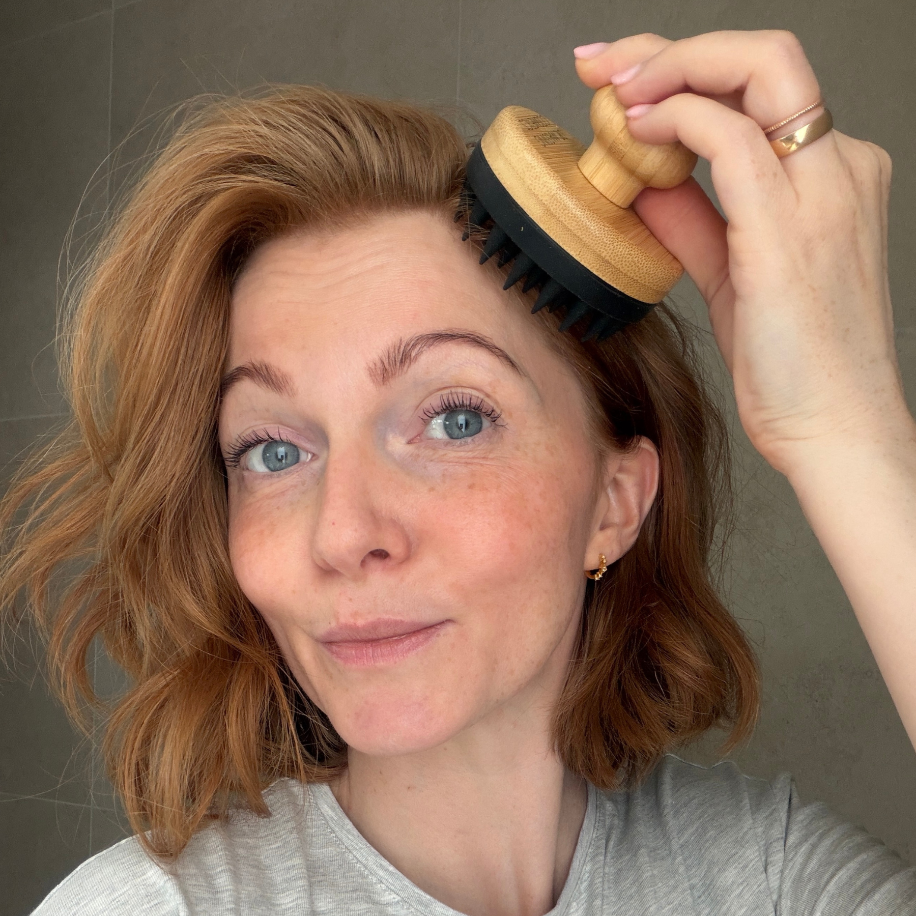 Eine junge Frau massiert ihre Kopfhaut mit dem Kopfmassager