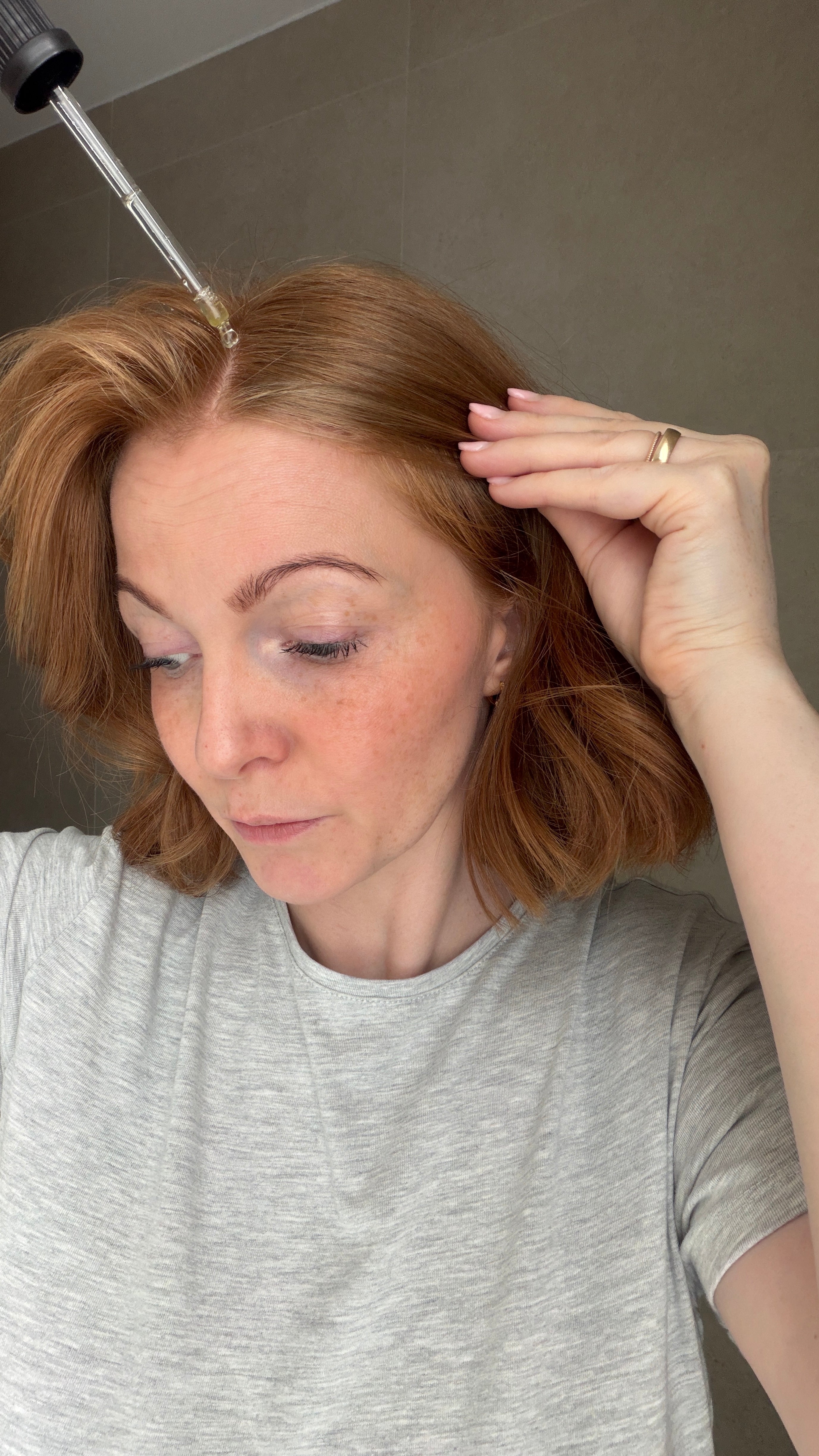 Eine junge Frau trägt mit einer Pipette das Full Hair Haarserum auf die Kopfhaut auf