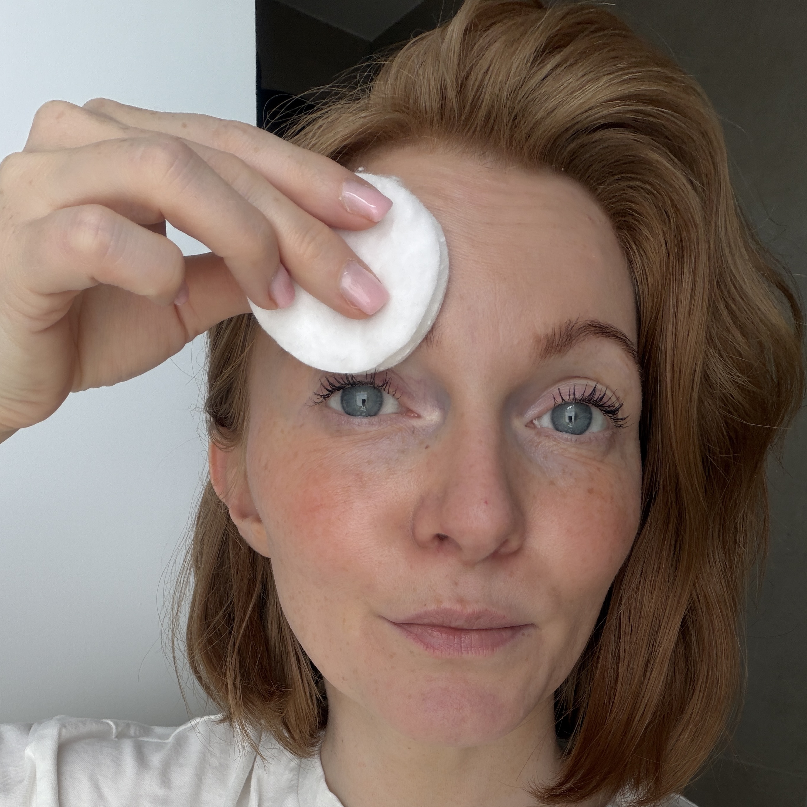 Eine junge Frau die sich mit einem Abschminkpad über die Augenbrauen wischt