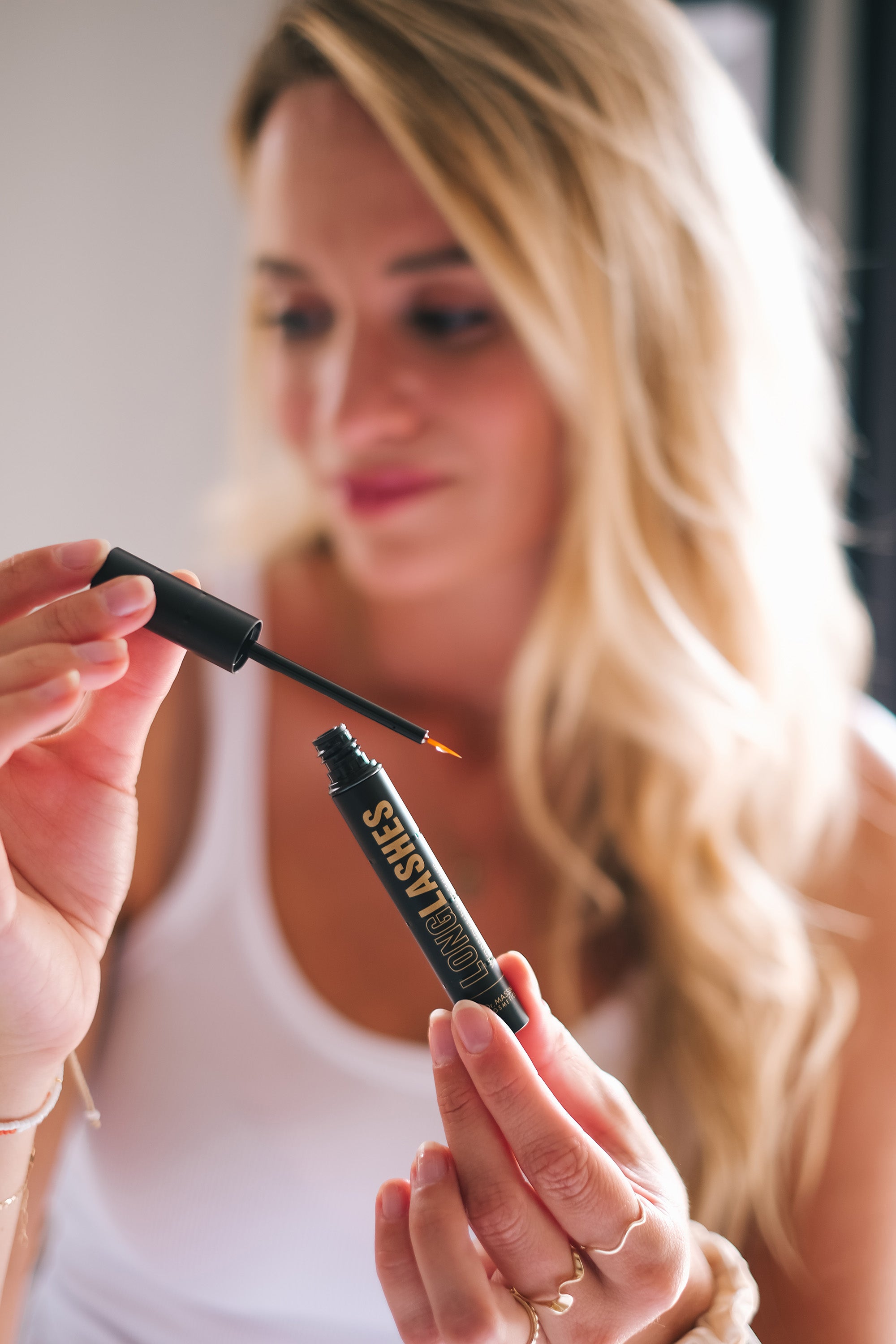 Eine lächelnde Frau hält Long Lashes Classic in die Kamera