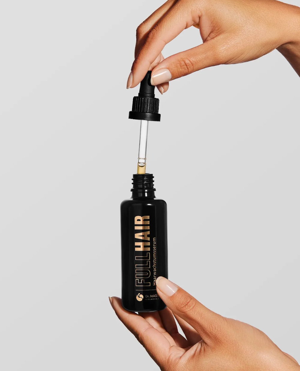 Frau hält Full Hair Serum in der Hand und hat die Pipette in der oberen Hand
