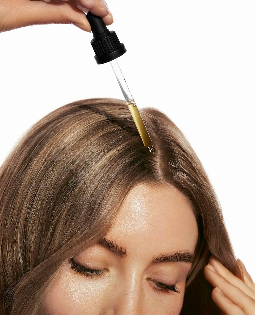Nahaufnahme der Anwendung des Haarserums mit Pipette direkt auf der Kopfhaut und Haarwurzel