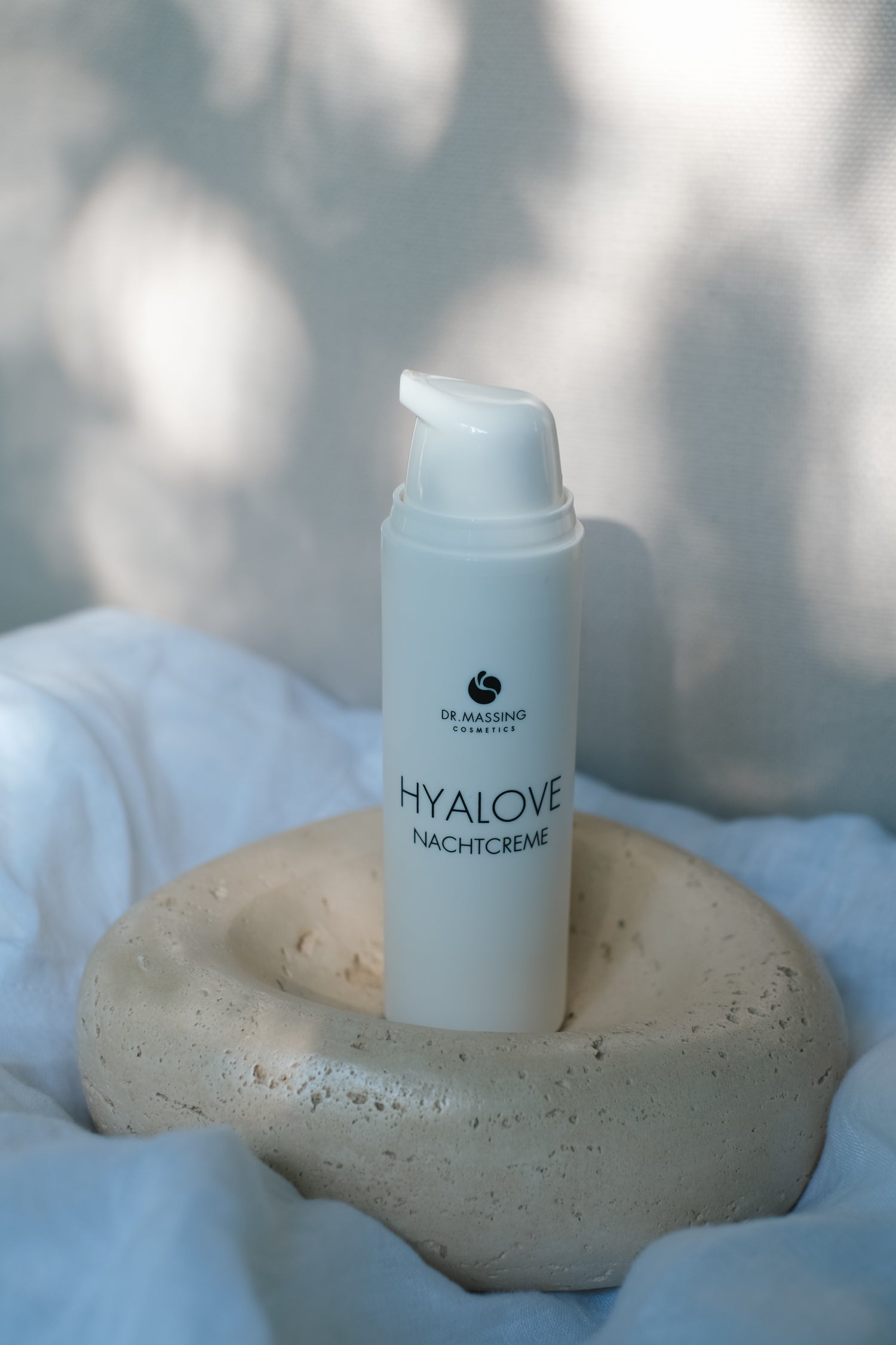 Produktbild von Hyalove Nachtcreme auf einem beigen Teller und weißem Bettlaken und Sonnenlicht Einstrahlung