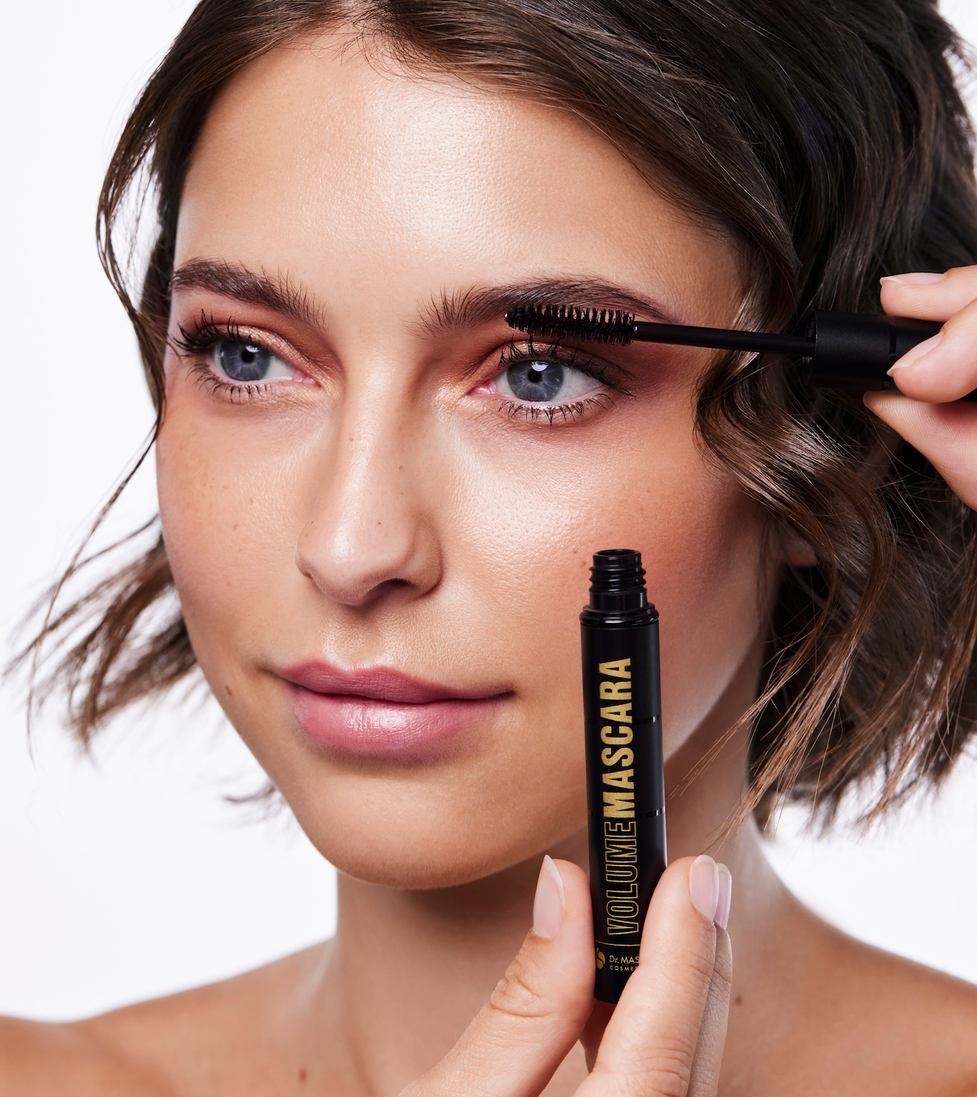 Portrait einer jungen Frau die Wimperntusche an den Wimpern anwendet
