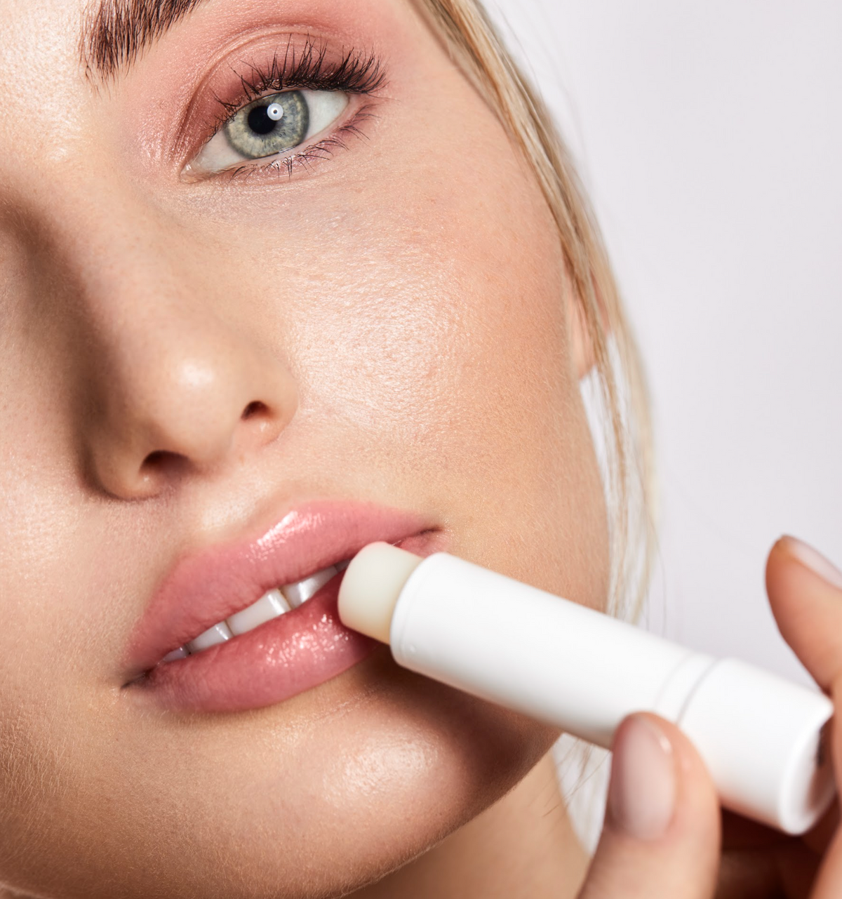 Frau schaut in die Kamera und trägt dabei die Lippenpflege von Dr. Massing auf die Lippen auf 