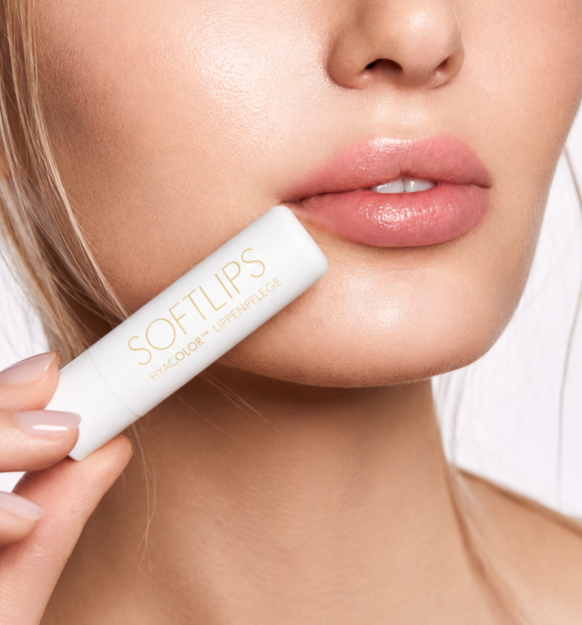 Frau mit vollen weichen Lippen hält Lippenpflege von Dr. Massing neben ihr Gesicht