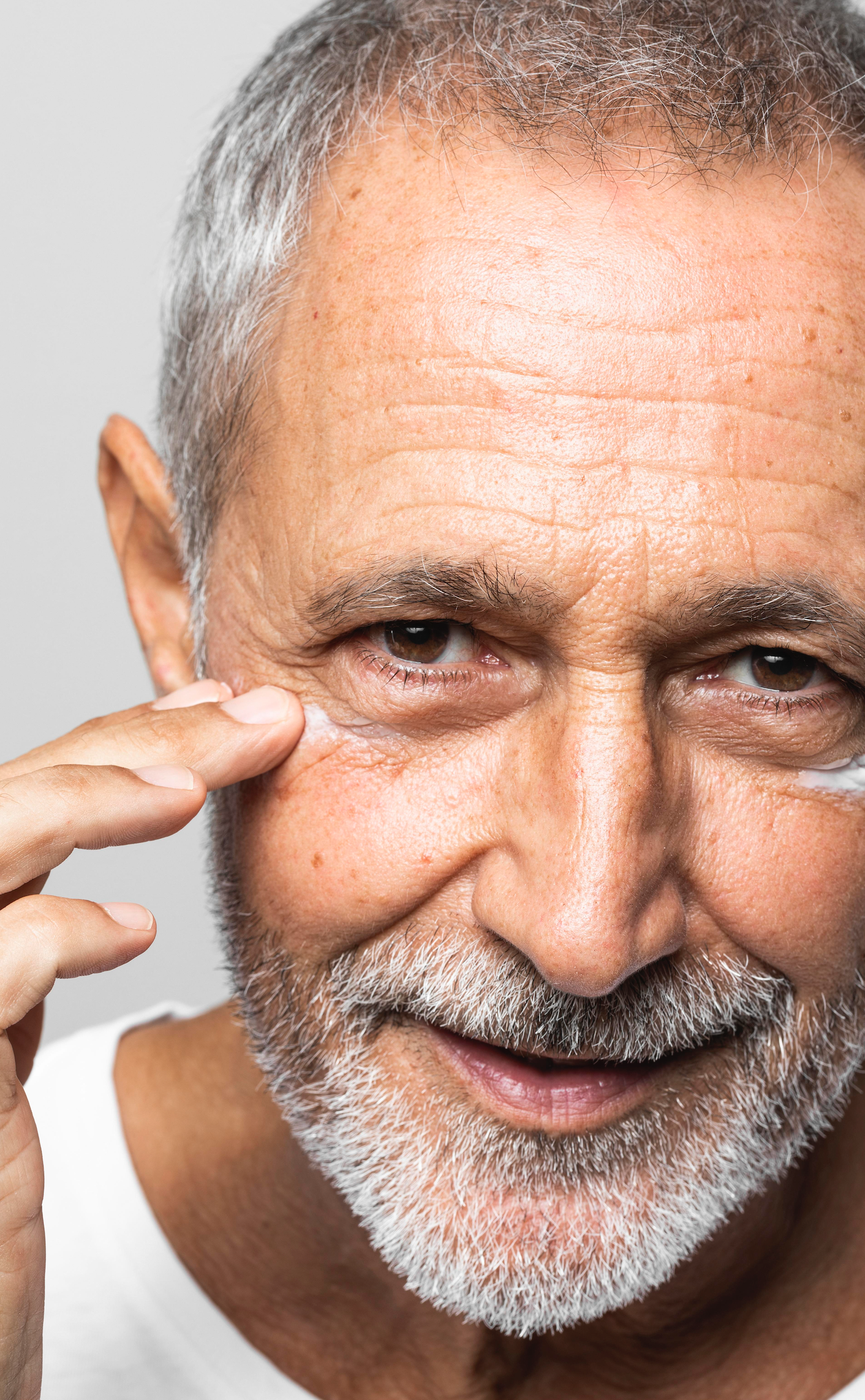 Portrait eines Mannes mit gepflegter reifer Gesichtshaut, die deutliche  Falten um die Augen und der Stirn aufweist.