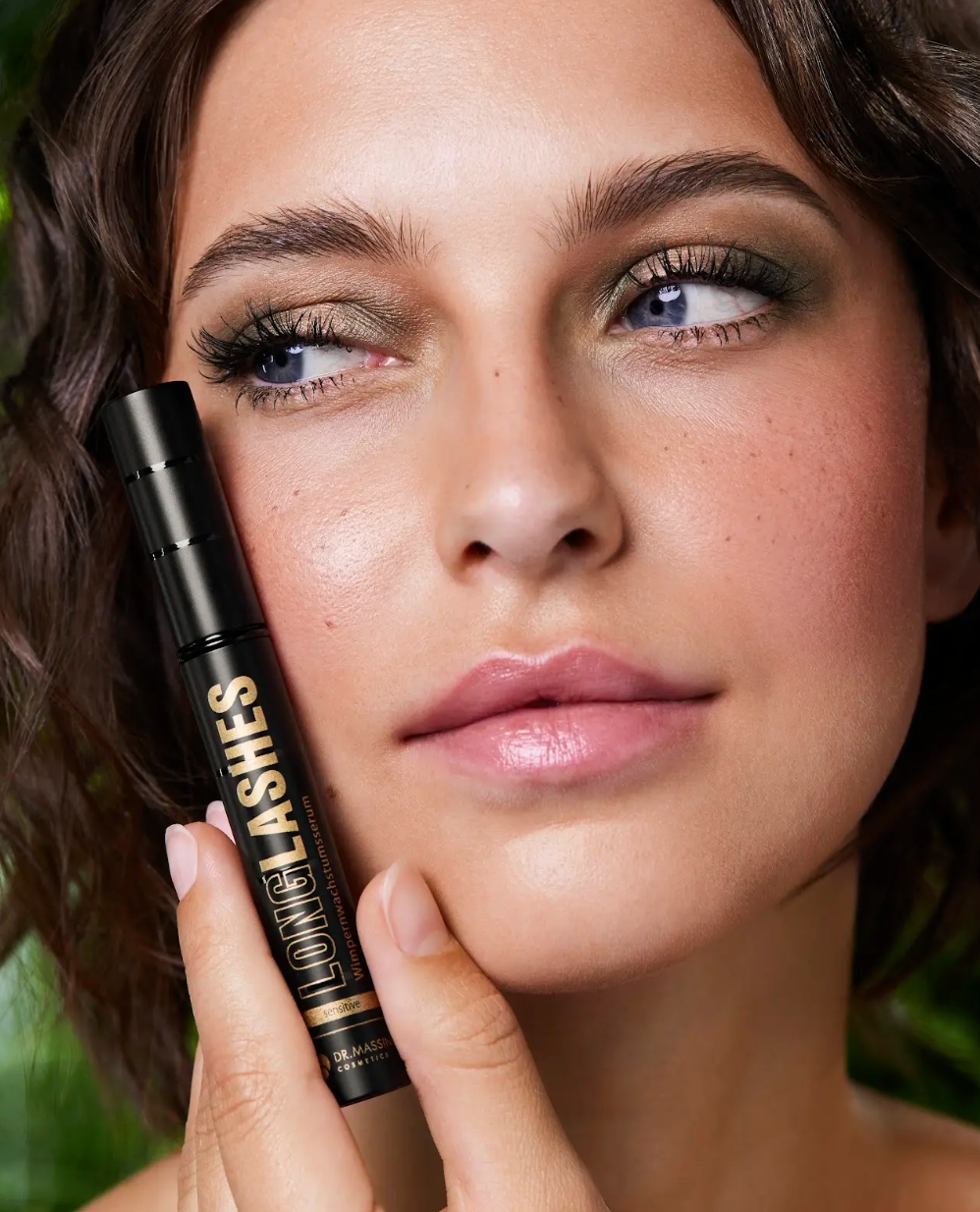 Junge Frau mit schönen langen Wimpern hält Sensitive Serum neben ihr Gesicht