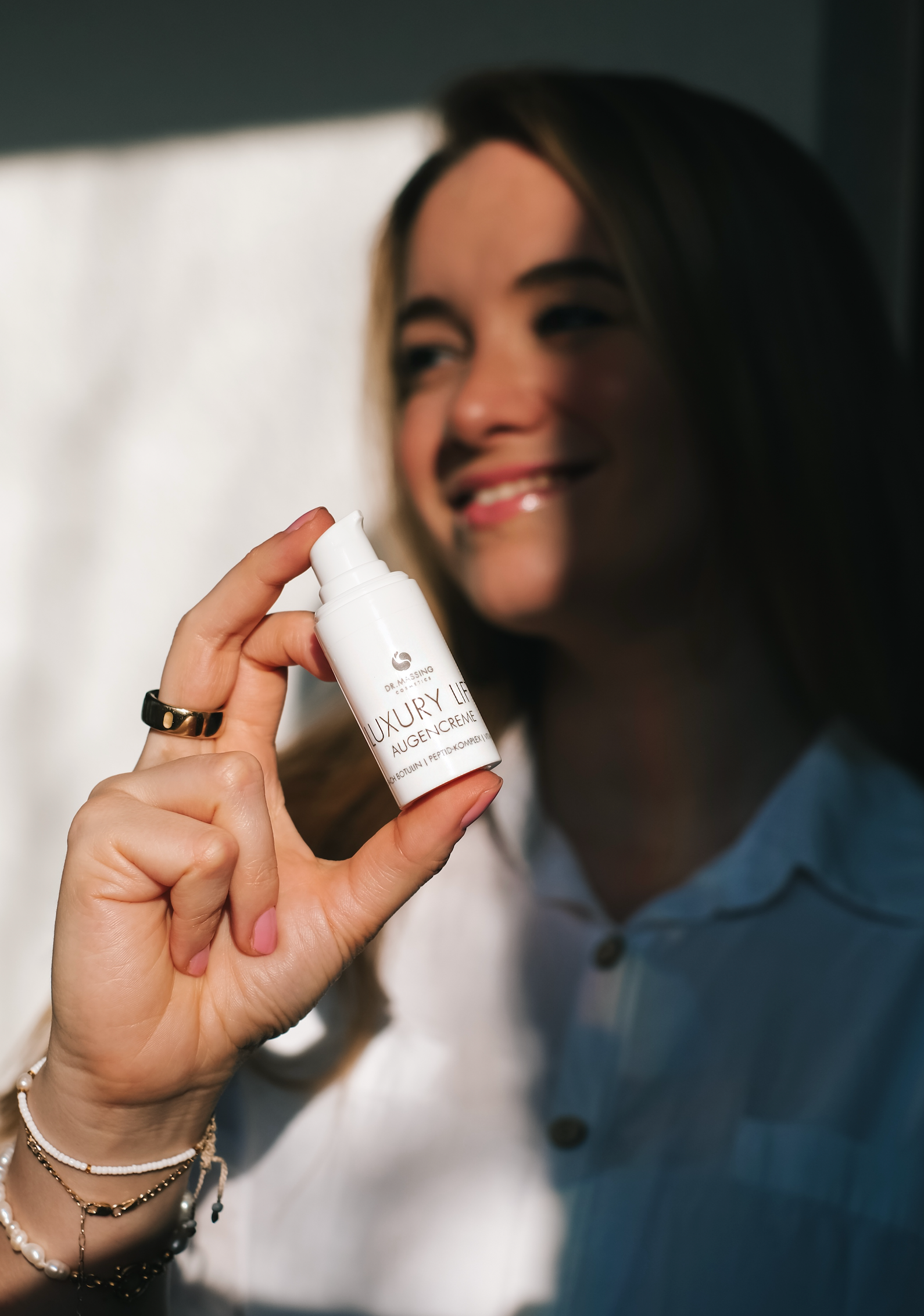 Frau hält Creme in der Hand und ist glücklich über Ergebnis.