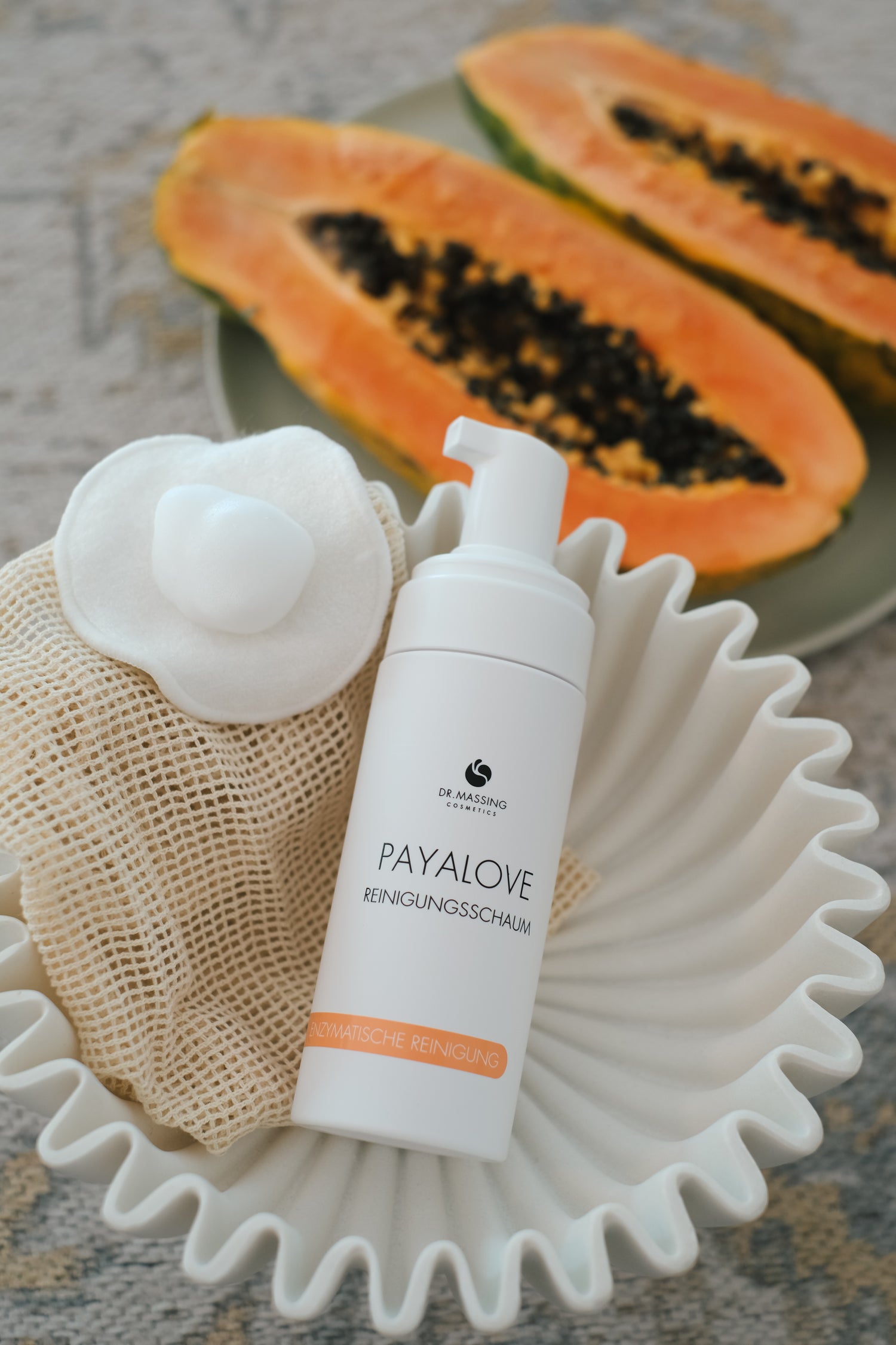 Payalove Reinigungsschaum liegt in beiger Schale neben Papaya und Wattepad mit Schaumtextur