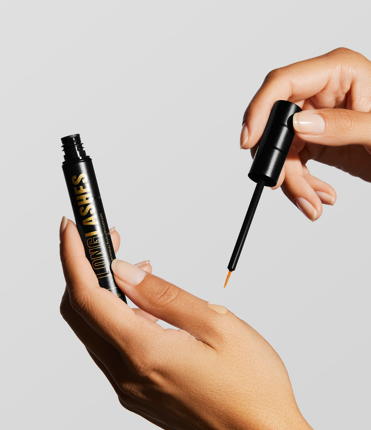 Zwei Hände die Long Lashes Classic Wimpernserum anwenden und Serum Flüssigkeit aus Fläschchen herausziehen
