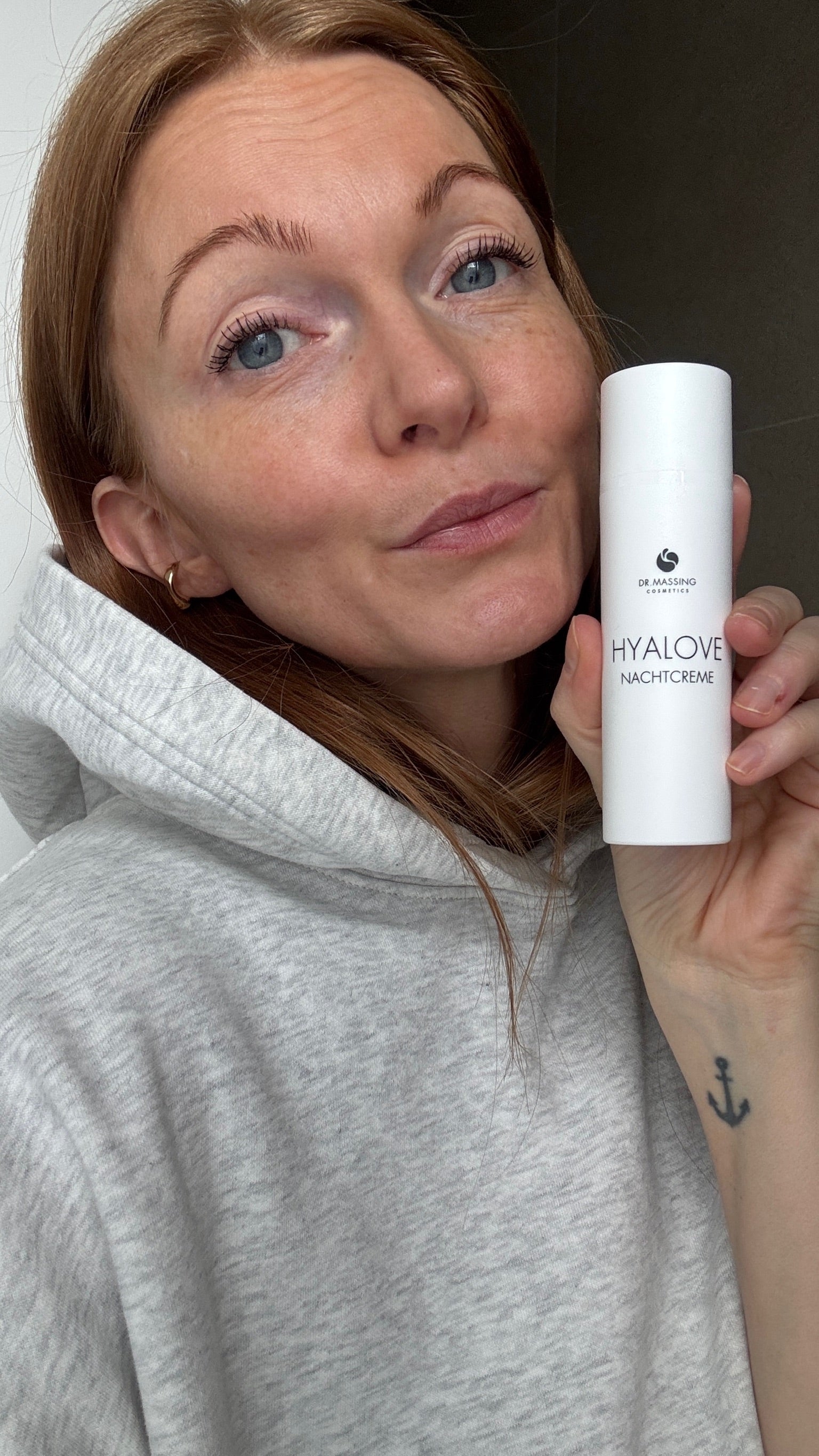 Frau hält Nachtcreme von Dr. Massing neben ihr Gesicht in der Hand und schaut in die Kamera