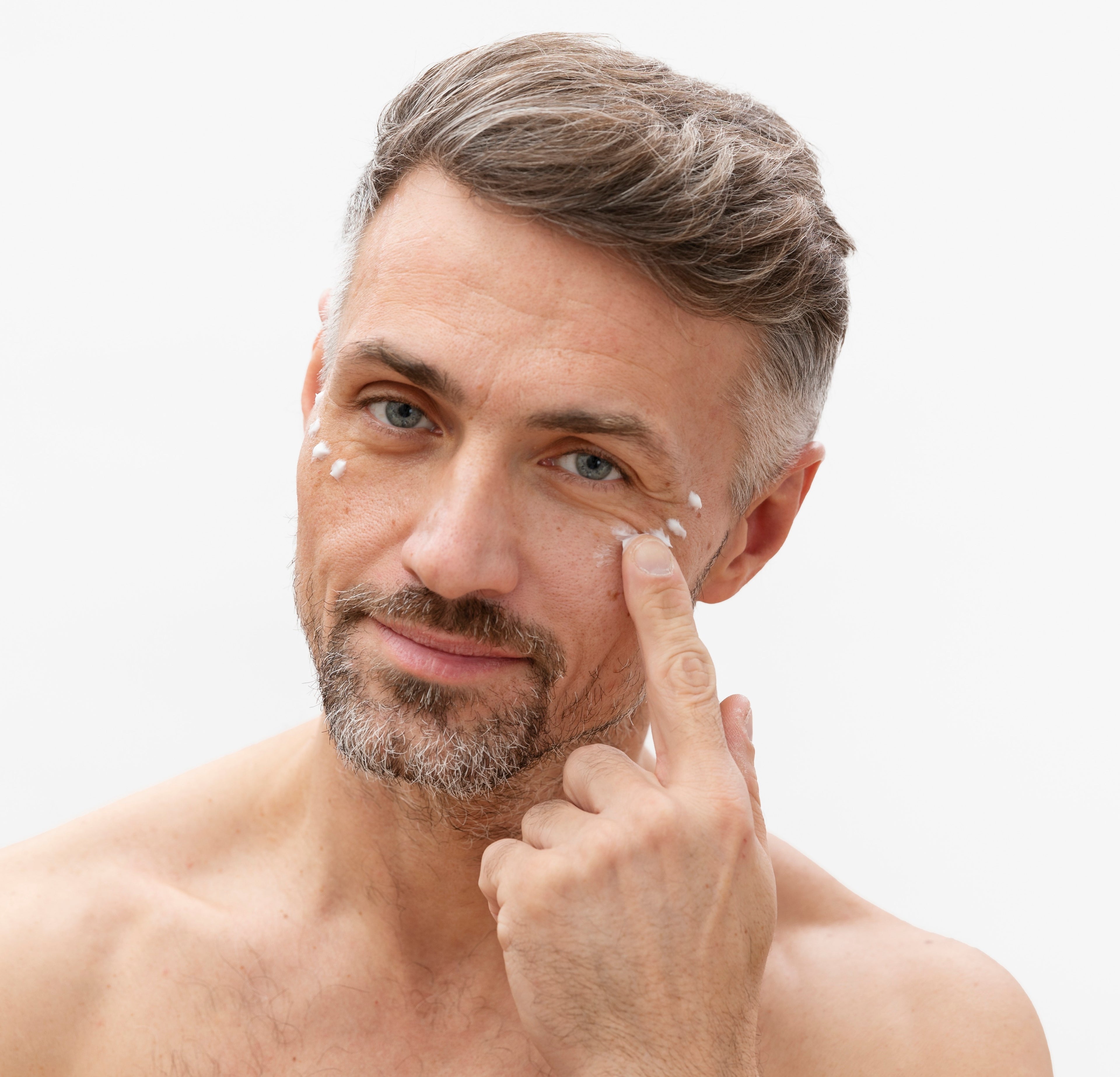 Mann mit reifer Haut uns Falten rund um die Augen benutzt Augencreme um Linien und Schwellungen zu reduzieren