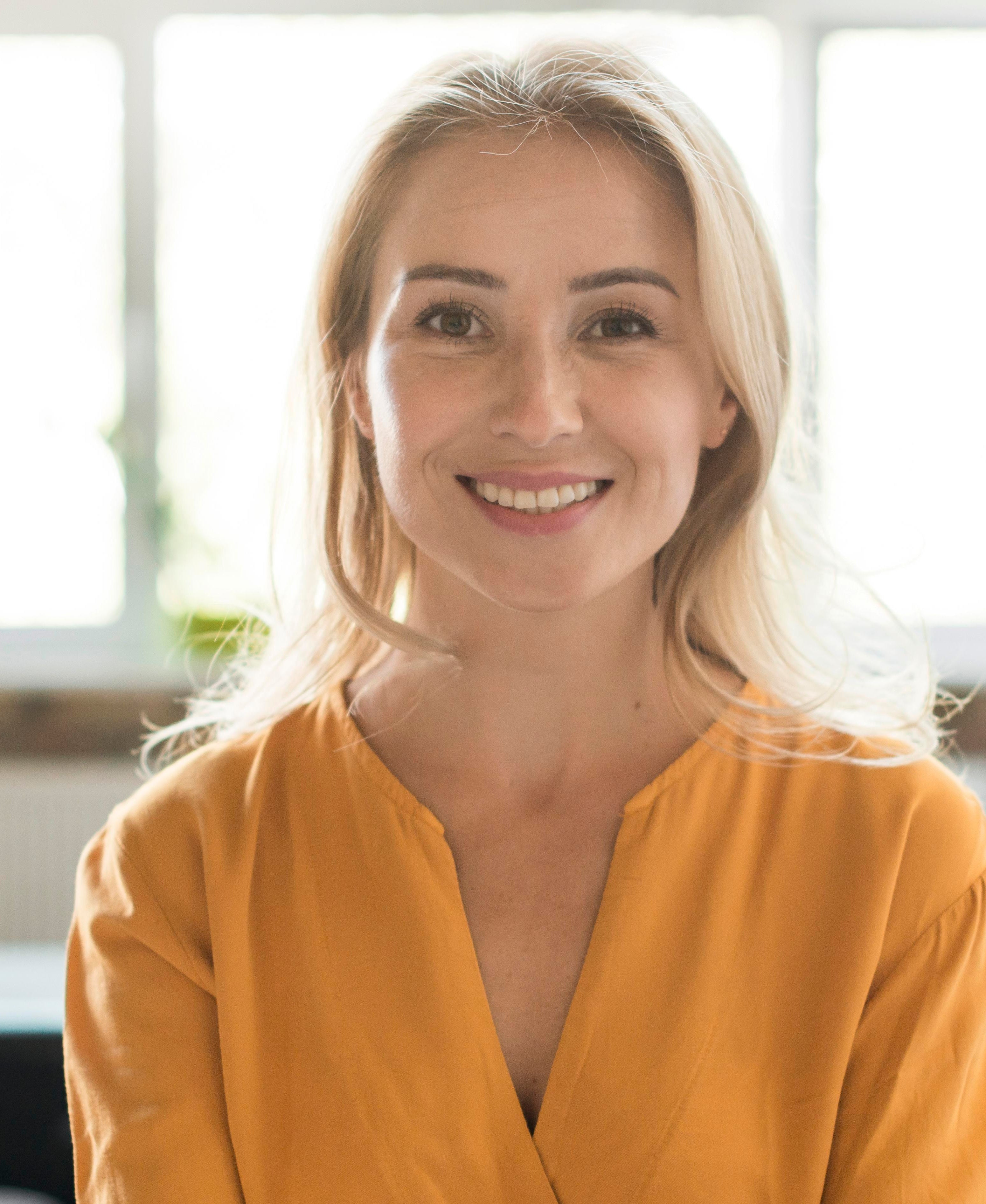 Portrait einer älteren Frau mit schönen vollen Wimpern schaut gerade in die Kamera und lächelt leicht