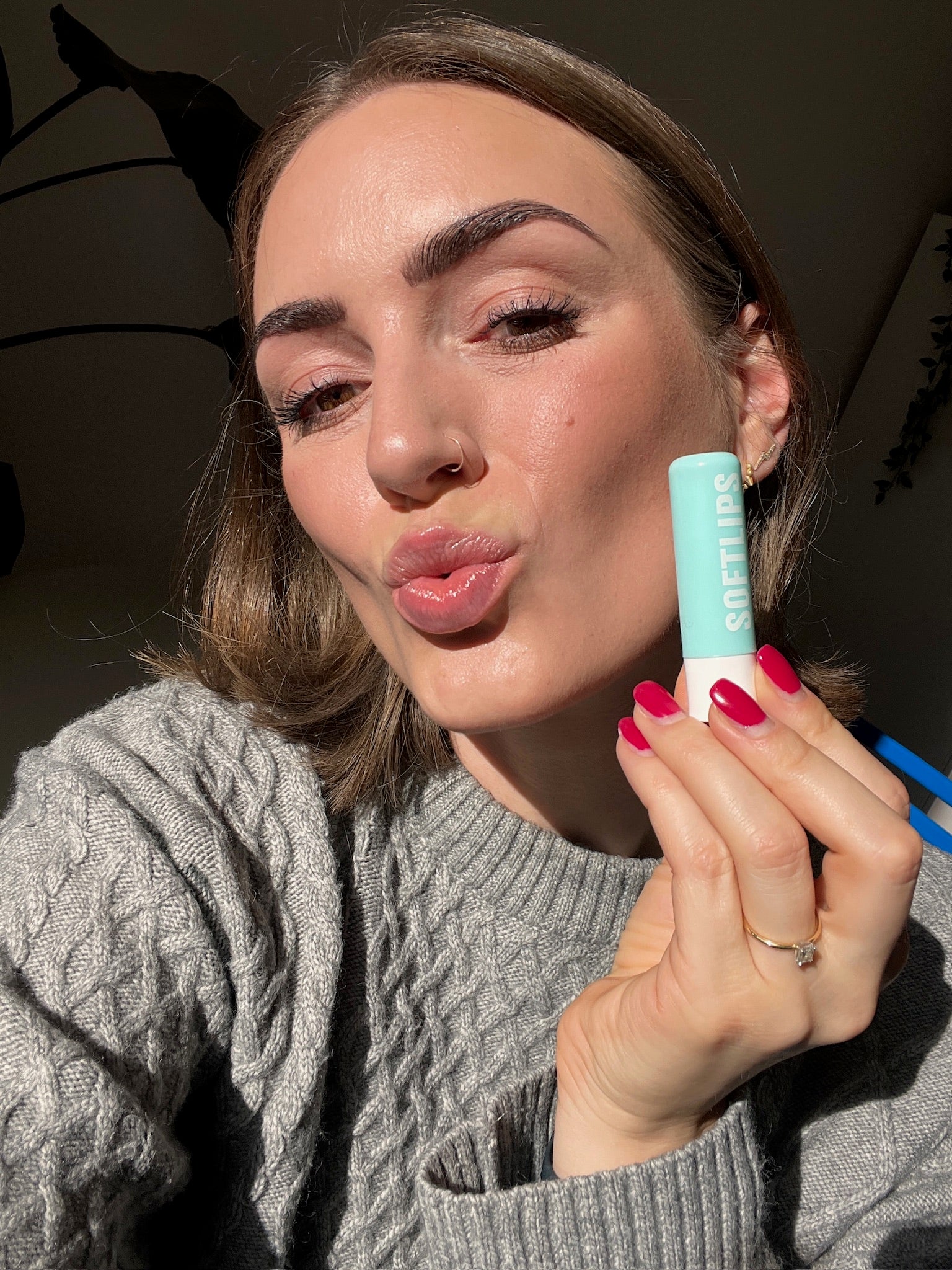Frau hält Softlips Petrol neben ihr Gesicht
