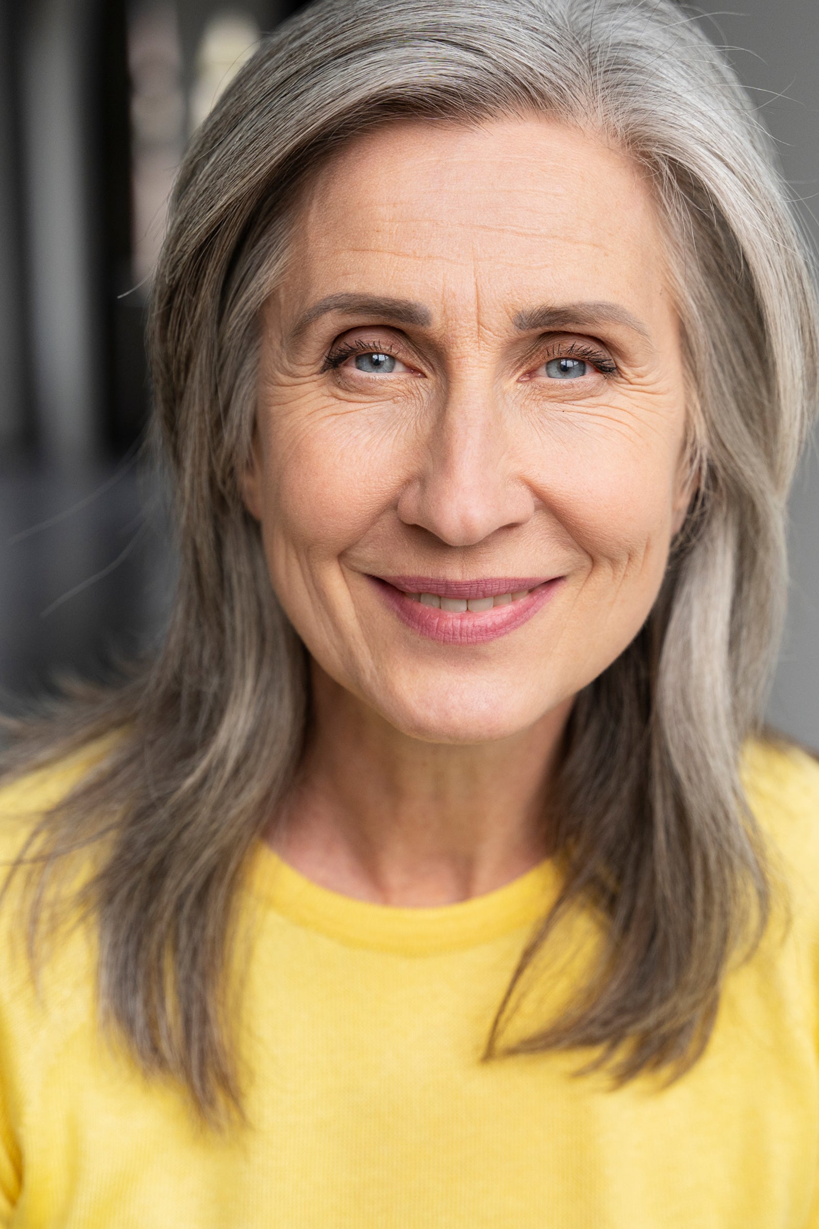 Portrait einer Frau mit reifer Gesichtshaut, die lächelnd in die Kamera sieht