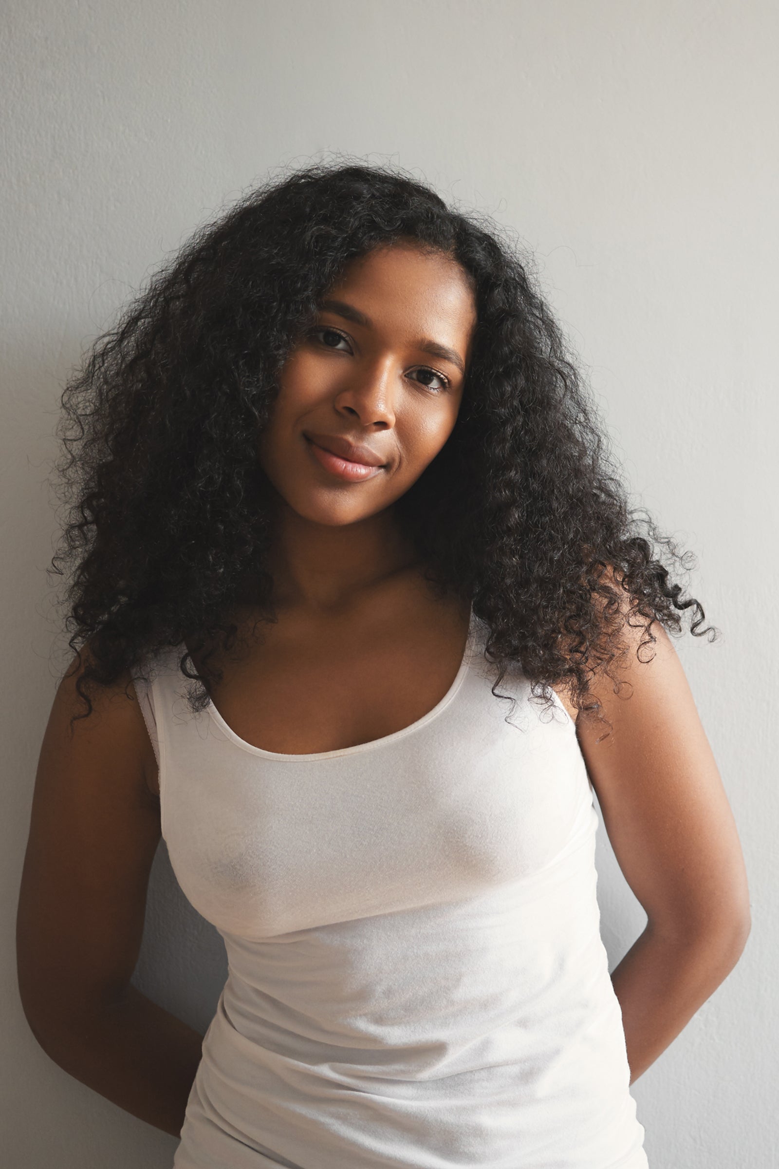 Portrait einer jungen Frau mit voluminösen Haaren und gepflegter Gesichtshaut.