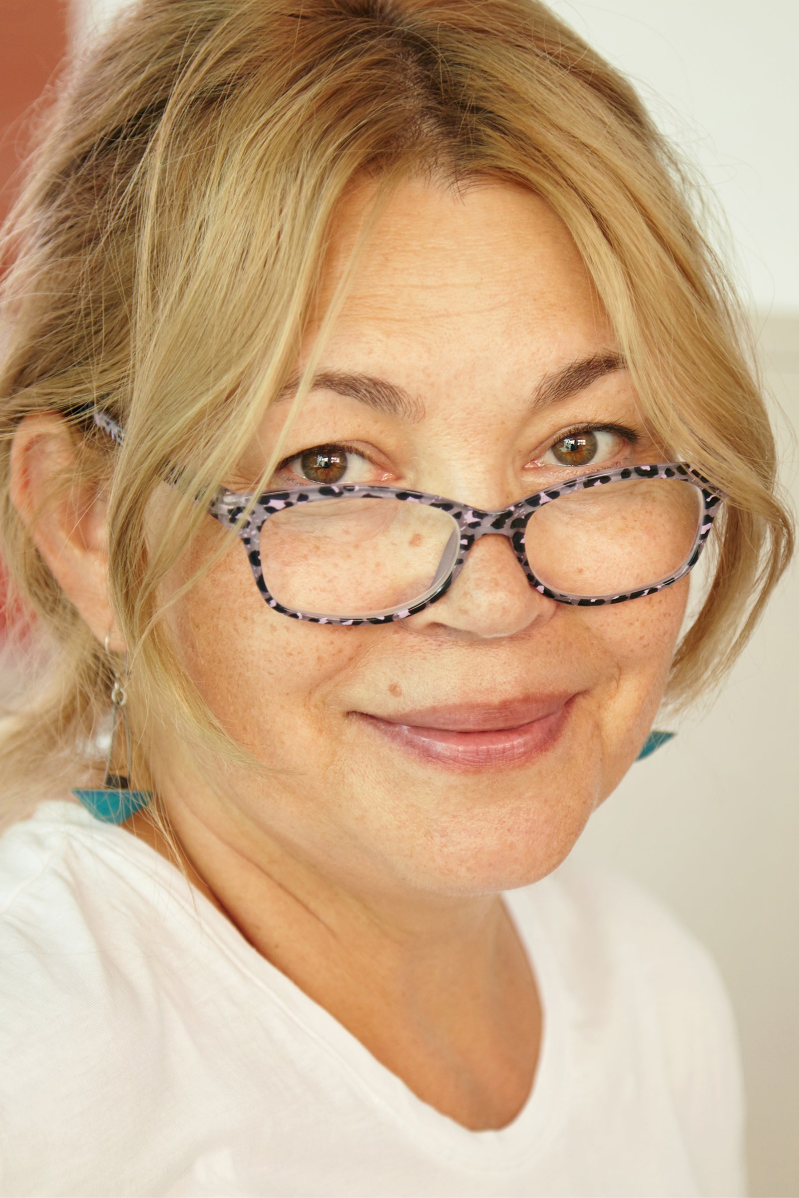 Portrait einer Frau mit reifer aber gepflegter Gesichtshaut und Sommersprossen, die lächelnd in die Kamera sieht.