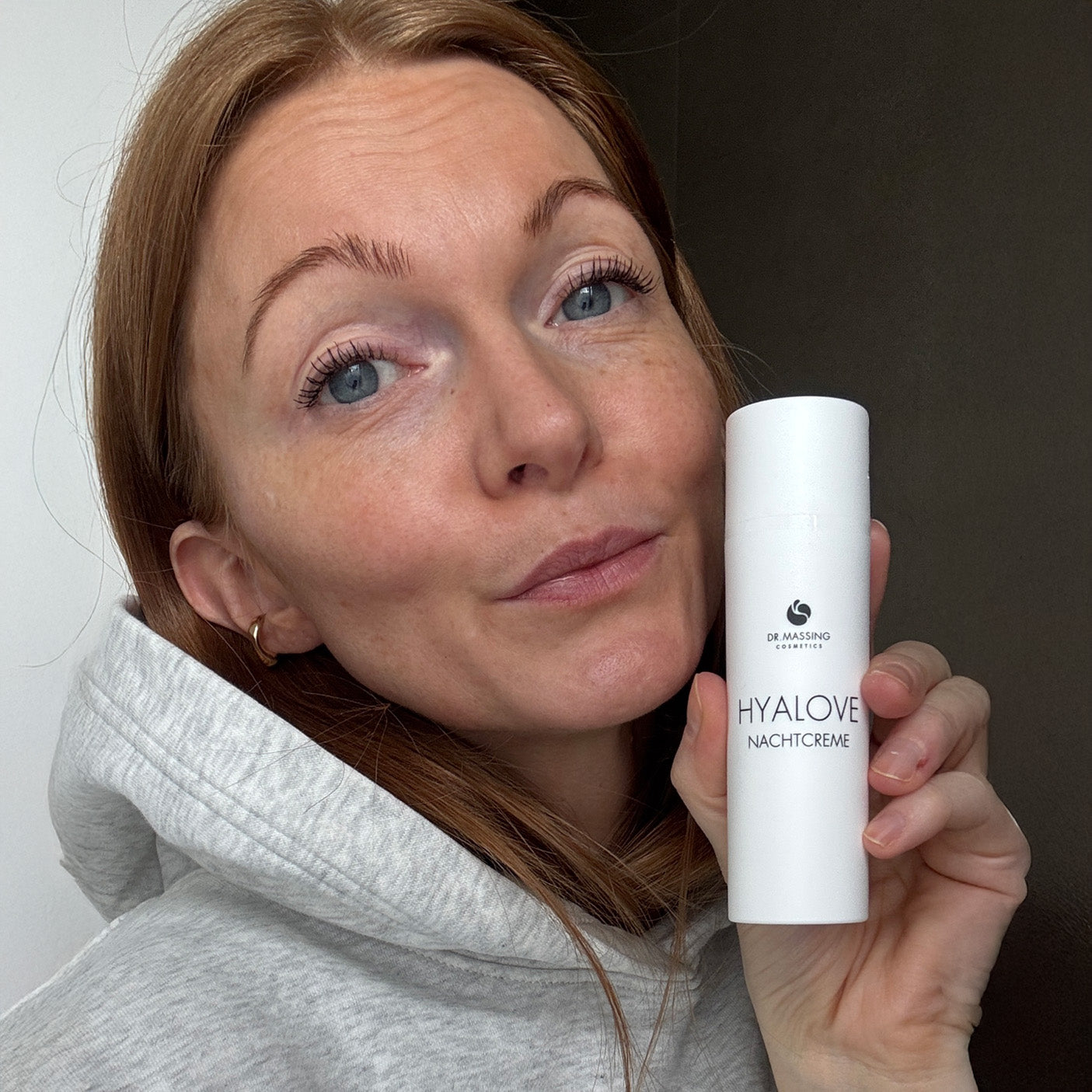 Nahaufnahme einer Frau welche die Hyalove Nachtcreme neben ihrem Gesicht in der Hand hält.
