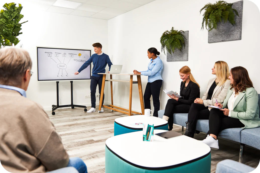 Niklas Massing zeigt seinem Team neue Ideen vor, Teammitglieder sitzen in gemütlicher Meeting Area