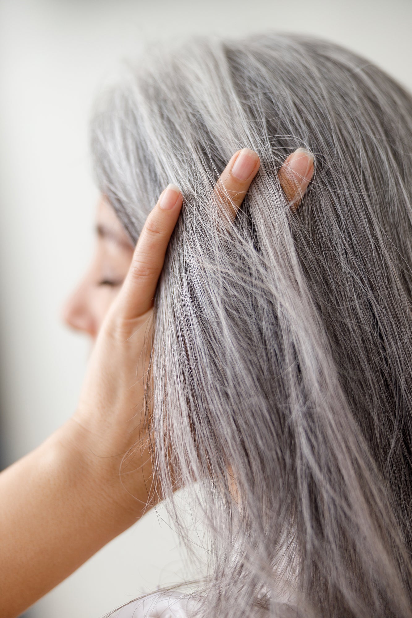Portrait einer Frau die sich mit der Hand durch die langen grauen Haare fährt