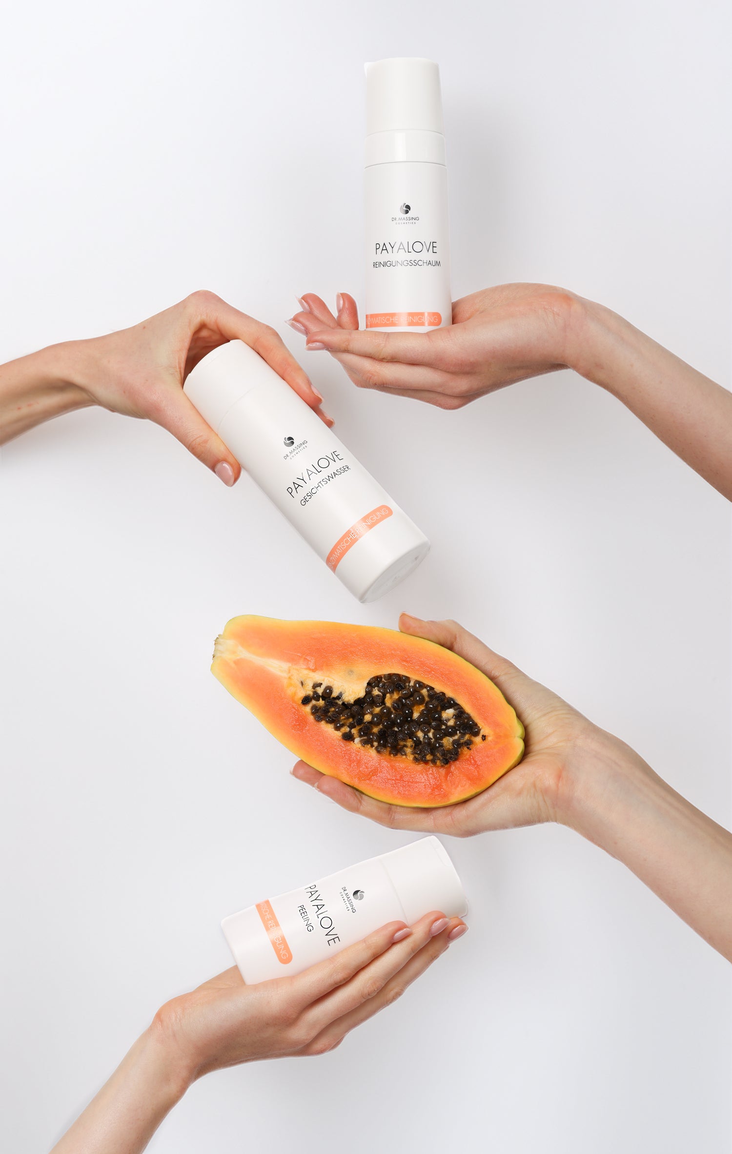 Bild zeigt Hände, die die Payalove Produkte Gesichtswasser, Peeling und Reinigungsschaum und eine Papaya halten