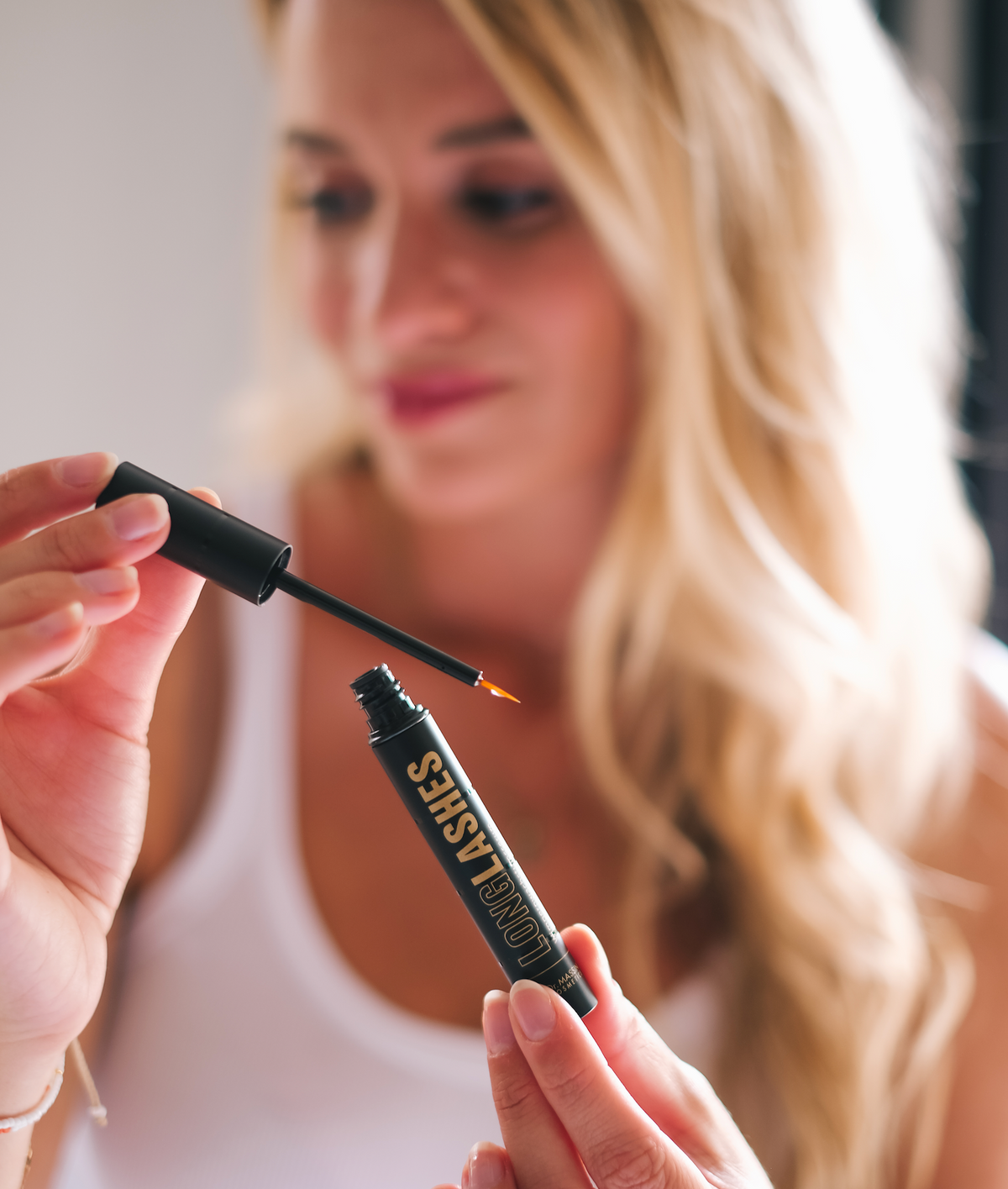 Eine lächelnde Frau hält Long Lashes Classic in die Kamera