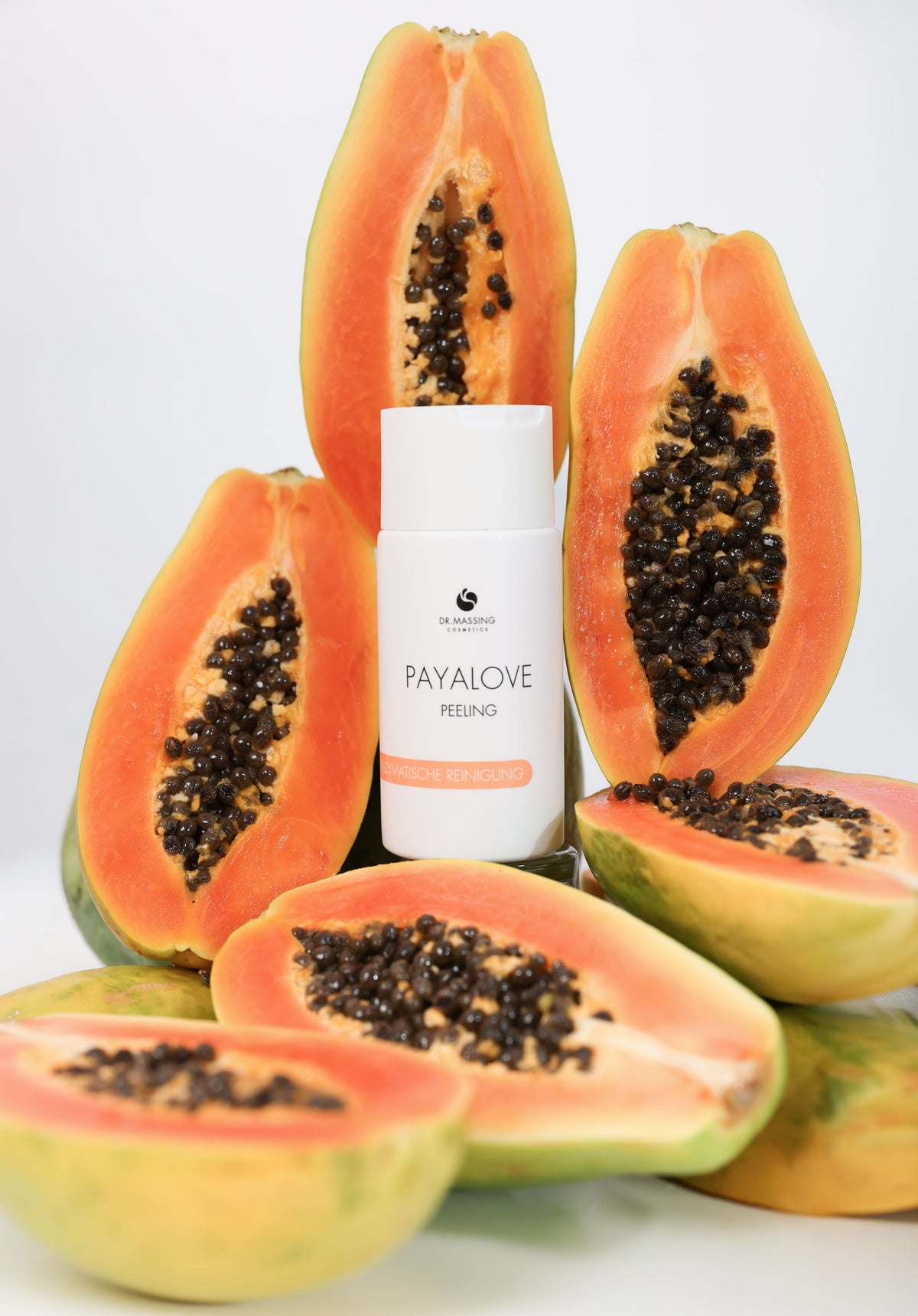 Payalove Peeling Produkt von Dr. Massing steht mittig auf Papayas