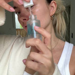 Frau trägt Hyaluronserum auf Augenpads auf und legt sie unter die Augenpartie um Falten, Schwellungen und Augenringe zu reduzieren