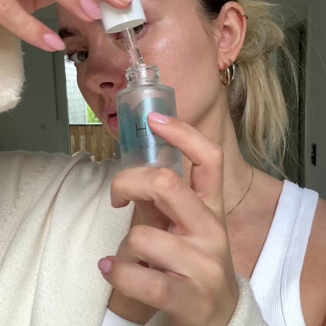 Frau trägt Hyaluronserum auf Augenpads auf und legt sie unter die Augenpartie um Falten, Schwellungen und Augenringe zu reduzieren
